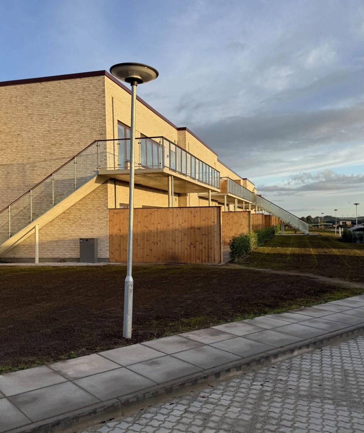 Foto: gavl og facade med udvendig trappe, træhegn og ny græsplæne